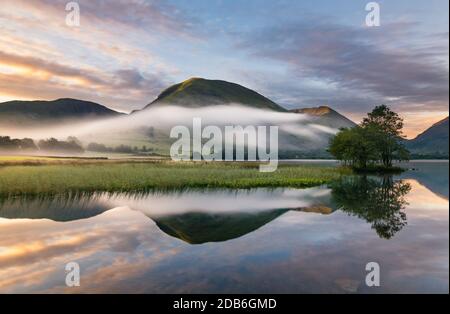 Ein wunderschöner Sommersonnenaufgang mit morgendlichen Nebel, der durch das Tal im englischen Lake District rollt. Stockfoto