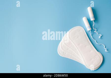 Feminines Sanitärpolster und Tampons auf blauem Hintergrund. Konzept der weiblichen Hygiene während der Menstruation. Konzept kritischer Tage. Flache Lage, Draufsicht Stockfoto