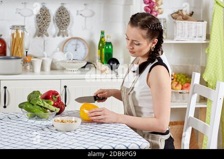 Junge Frau in einer Schürze kocht gesundes Essen in der Küche. Stockfoto