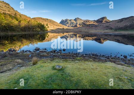 Weitwinkelansicht von Blea Tarn im englischen Seengebiet an einem sonnigen Frühlingsmorgen mit klarem Himmel und Reflexionen. Stockfoto