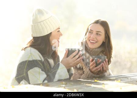 Zwei glückliche Freunde beim Frühstück sitzen im Winter neblig reden Morgens im Freien Stockfoto
