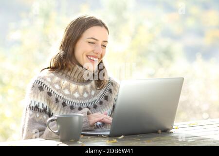 Glückliche Frau mit Laptop sitzen auf einem Tisch in der Berg im Herbst Stockfoto