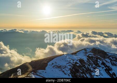 Schneebedeckter hoher Berg durch die Wolken am blauen Himmel Stockfoto