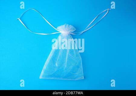 Tasche aus weißem, transparentem Synthetikmaterial für Geschenke und Kosmetik auf blauem Hintergrund, Draufsicht Stockfoto