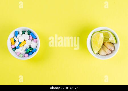 Limette und Ingwer gegen mehrfarbige Tabletten. Das Konzept der Wahl einer gesunden Ernährung gegenüber der Einnahme von Medikamenten. Von oben mit viel Platz. Stockfoto