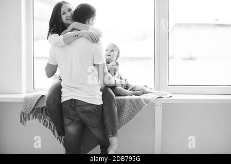 Porträt einer glücklichen jungen Familie mit kleinen Tochter posiert am Fenster in hellen Raum. Stockfoto