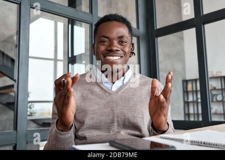 Glücklicher afrikanischer Geschäftsmann, der ein Headset trägt und mit der Kamera spricht, mit der Webcam. Stockfoto