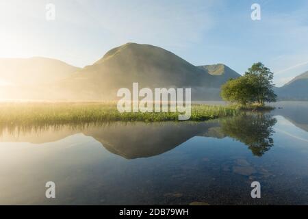 Klare Reflexionen der Berge im See an einem nebligen Sommermorgen in Brotherswater im Lake District. Stockfoto