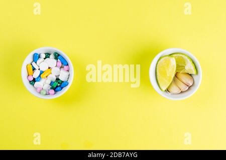 Limette und Ingwer gegen mehrfarbige Tabletten. Das Konzept der Wahl einer gesunden Ernährung gegenüber der Einnahme von Medikamenten. Von oben mit viel Platz. Stockfoto