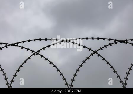 Barbwire gegen düsteren grauen Himmel Stockfoto