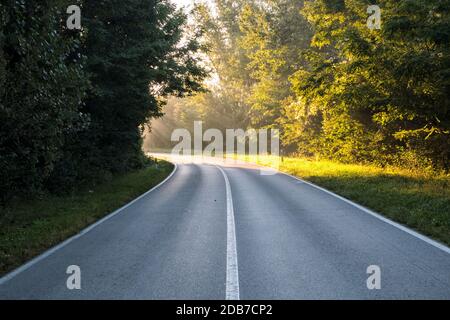 Die Straße, die an der Biegung durch Sonnenlicht beleuchtet wird. Sie vertreten die Inspiration, Gottes Erscheinungen, Aufklärung Stockfoto