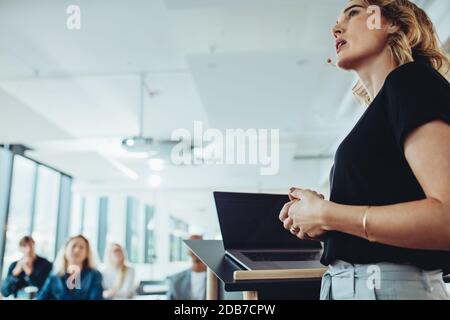 Low-Angle-Aufnahme einer selbstbewussten Geschäftsfrau, die eine Präsentation auf einer Konferenz vorstellt. Sprecherin teilt Geschäftsplan mit Kollegen. Stockfoto