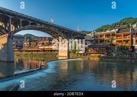 Feng Huang, China - August 2019: Lange Zeit ist die Verbindung der Straßenbrücke über den Fluss Tuo Jiang und Holzhäuser in der alten Altstadt von Fenghuang bekannt Stockfoto