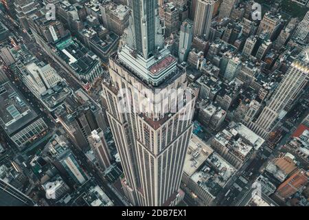 Atemberaubende Aussicht auf das Empire State Building in Manhattan, New York City, umgeben von Wolkenkratzer-Dächern und Straßen Stockfoto