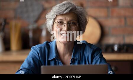 Kopf erschossen Porträt lächelnd reife Frau trägt Brille mit Laptop Stockfoto