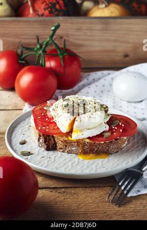 Offenes Sandwich, Toast mit Tomaten und pochiertem Ei. Stockfoto