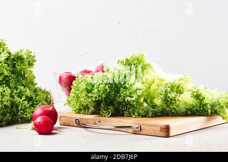 Frischer grüner Salat und Rettich auf dem Küchentisch. Salat kochen. Stockfoto