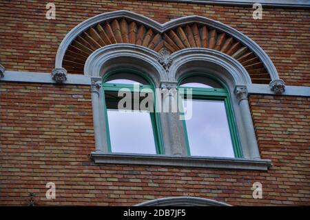 Doppeltes Bogenfenster auf einer Ziegelfassade der mittelalterlichen Wand. Biforium - antike Fenster mit Säule, alte Architektur-Element, dekorative Details. Stockfoto