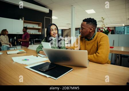Junge Unternehmer diskutieren Arbeit während der Recherche auf Laptop und digital Tablet im Büro Stockfoto
