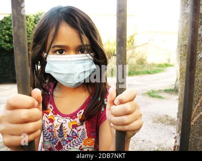 Foto eines kleinen Mädchens, das eine Maske trägt und hält Balken Stockfoto