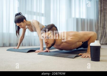 Morgen Fitness-Training von Familie paar zu Hause. Aktive Mann und Frau in Sportbekleidung tun Push-up-Übung in ihrem Haus, gesunde Lebensweise, Physik Stockfoto