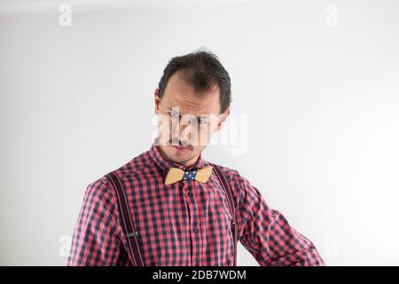Studio-Porträt eines Mannes mit Holzbowtie, Hosenträger und Hemd. Dreißig Jahre alter Mann mit Schnurrbart, der die Kamera anschaut und Geste macht. Stockfoto