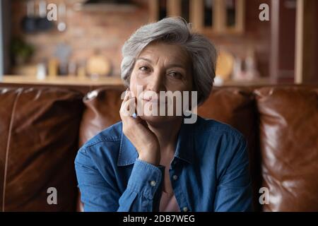Kopf erschossen Porträt reife Frau sitzt auf der Couch allein Stockfoto
