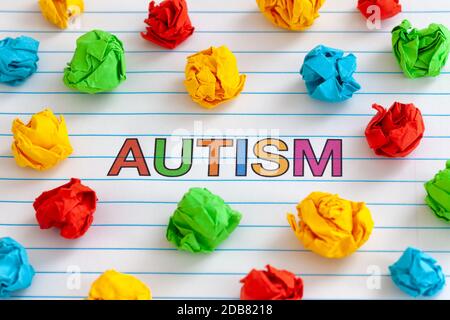 Autismus. Autismus-Spektrum-Störung. Autismus-Wort auf Notizbuchblatt mit bunten zerknautelten Papierkugeln um sie herum. Nahaufnahme. Stockfoto