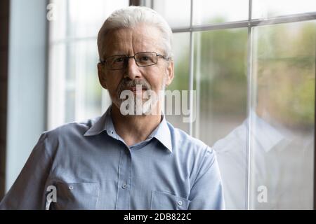 Kopf erschossen Porträt reifen Mann trägt Brille in der Nähe Fenster stehen Stockfoto