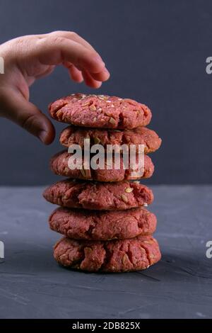 Die Hand des Kindes, das nach frisch gebackenen Rüben-Chip-Haferflocken auf einem Blecktisch greift. Feiertag- und Kochkonzept. Selektiver Fokus Stockfoto