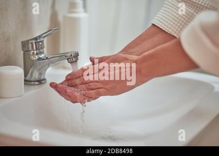 Frau waschen Hände mit Wasser im Waschbecken im Badezimmer zu Hause, Nahaufnahme. Beauty, Hautpflege und Kosmetologie Konzept Stockfoto