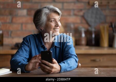 Nahaufnahme lächelnd verträumte reife Frau abgelenkt von Online-Chat Stockfoto