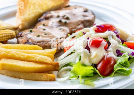 Gemüsesalat mit Nahaufnahme und Mayonnaise mit Tomate, Zwiebel, Salat, Purpurkohl und Steakporschhack mit Pfeffersoße und pommes frites Stockfoto