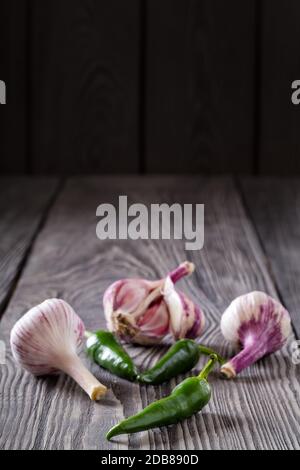 Knoblauch und würziger grüner Pfeffer auf einem Holztisch. Gewürze, Gewürze. Das Konzept der natürlichen Nahrung und eine reiche Ernte. Stockfoto