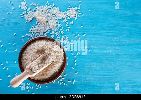 Tonschale mit Reiskörnern auf blauem Hintergrund. Blick von oben. Das Konzept der gesunden natürlichen Lebensmitteln. Stockfoto