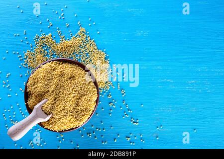 Tonschale mit Hirse auf blauem Hintergrund. Blick von oben. Das Konzept der gesunden natürlichen Lebensmitteln. Stockfoto