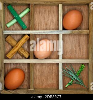 Ein Holzspiel aus Nullen und Kreuzen mit Eiern Wie die Nughts und Kräuter wie die Kreuze Stockfoto