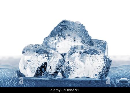 Stapel von großen Eiswürfeln mit Tröpfchen liegen auf dem Tisch. Isoliert auf weißem Hintergrund. Tonung in blau. Stockfoto