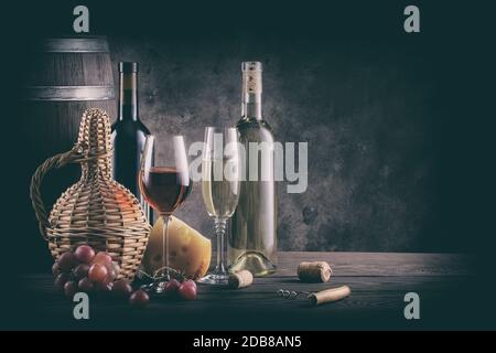 Wein noch Leben auf Holztisch. Verarbeitung für Jahrgang. Flaschen, Gläser, Fass- und Weintrauben mit Käse auf einem Holztisch. Stockfoto