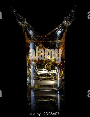 Ein Glas Whiskey und Splash isoliert auf einem schwarzen Hintergrund Stockfoto