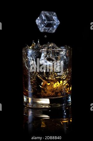 Eiswürfel in ein Glas Whiskey auf schwarzem Hintergrund Stockfoto