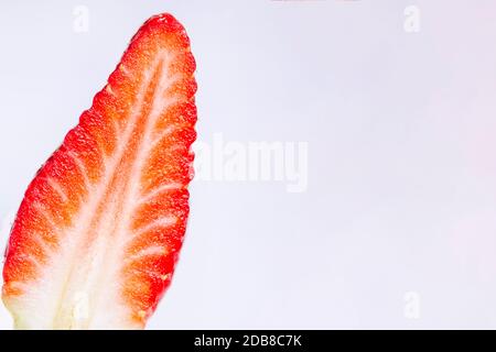 Nahaufnahme einer frischen, leuchtend roten Erdbeere in zwei Hälften auf weißem Hintergrund geschnitten, horizontal und Kopierraum Stockfoto