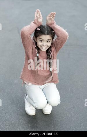 Frohe Ostern. Urlaub Bunny Girl posiert wie Kaninchen grauen Hintergrund. Kind lächelnd spielen Bunny Rolle. Verspieltes Baby feiern Ostern. Frühlingsferien. Talent und Handeln. Glückliche Kindheit. Cute Bunny. Stockfoto