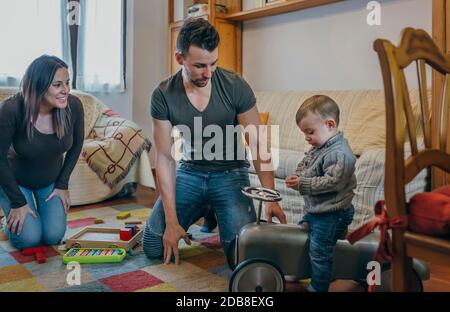 Eltern und ihr kleiner Sohn spielen mit einem kleinen Rennen Auto Stockfoto