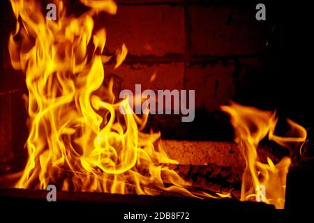 Gelbe Flammen im Feuer mit Holz und Holz. Nahaufnahme. Stockfoto