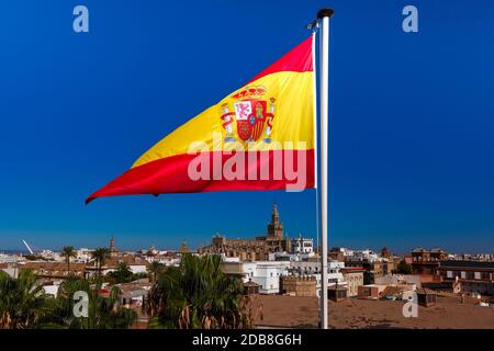 Die Flagge Spaniens, eine horizontale Trikolore aus Rot, Gelb und Rot, die mit dem spanischen Wappen über Sevilla, Spanien, versehen ist Stockfoto