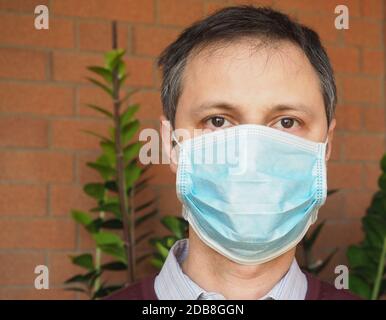 Mann mit chirurgischer Maske verwendet, um die Verbreitung Covid-19 Infektion zu stoppen Stockfoto