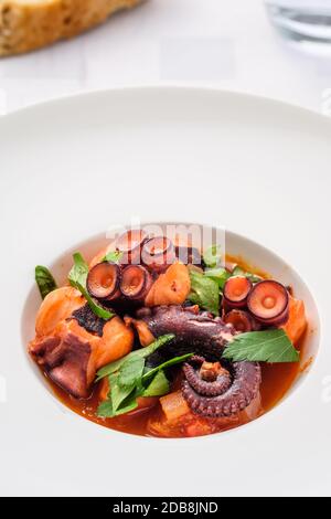 Oktopus mit Tomaten und Petersilie in vertikalem Format geschmort Stockfoto