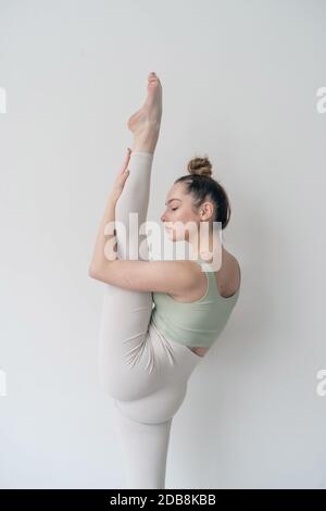 Porträt einer Frau, die an einer Wand steht, die sie streckt Bein in der Luft Stockfoto