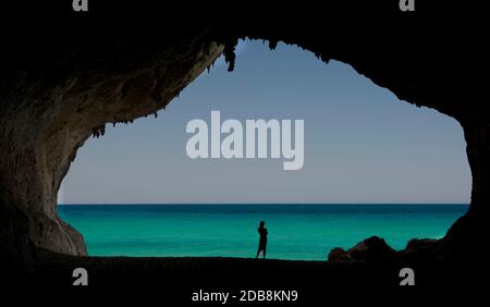 Silhouette einer Frau, die in einer Höhle am Strand steht, Sardinien, Italien Stockfoto